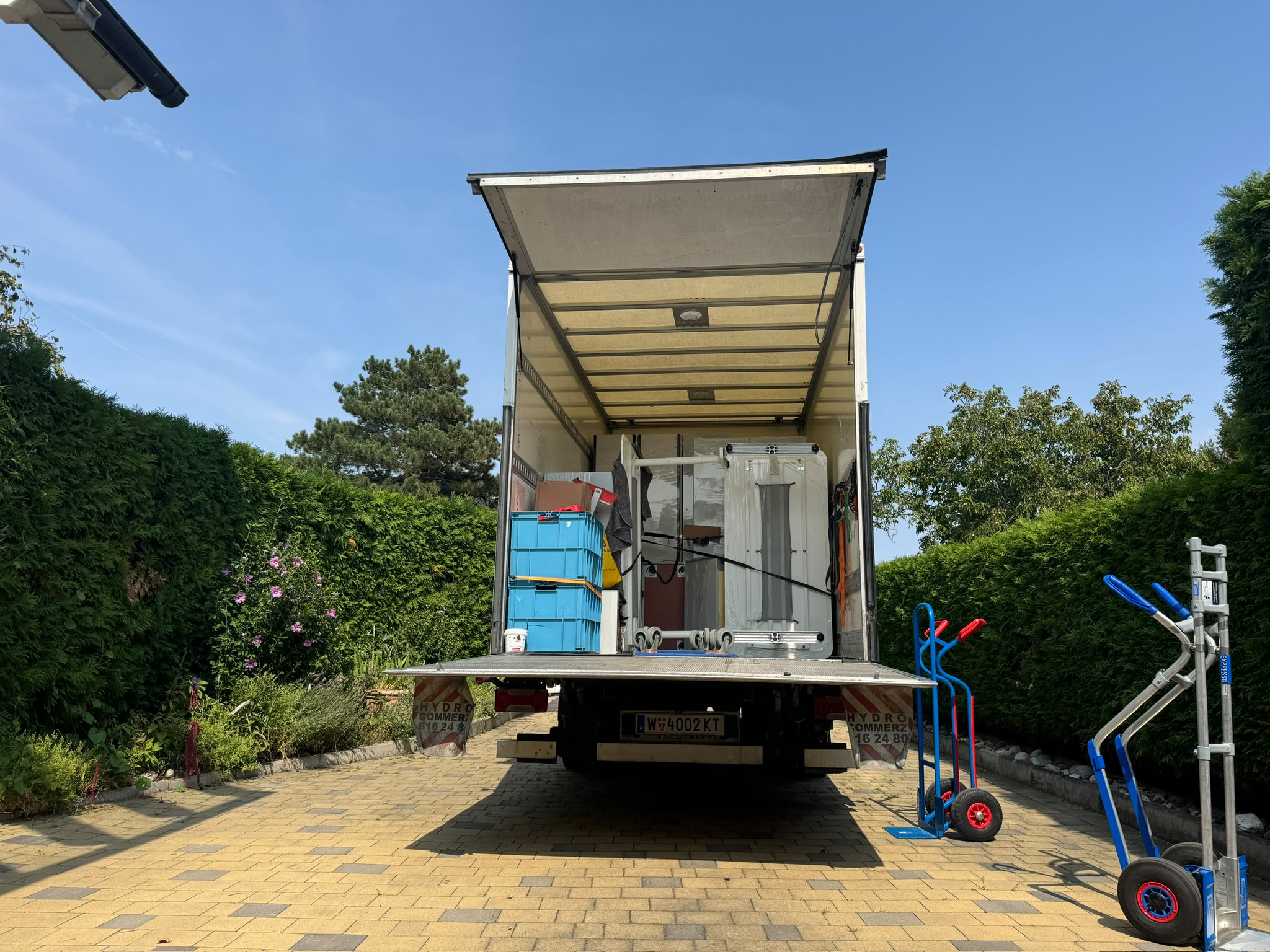 Beladener Umzugs-LKW mit Sackkarren in einer Einfahrt